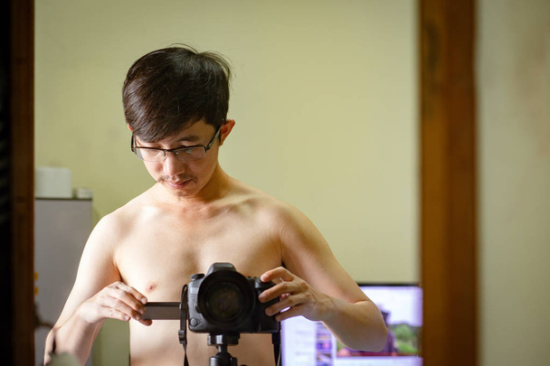 裸の男は三脚で写真を撮るためのDslrカメラを設定します。 - 写真・画像
