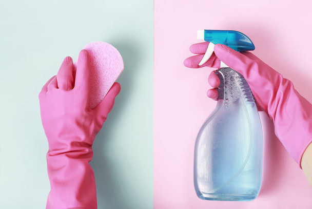 Female hands in glove holds window spray and sponge on pink and blue background, top view, spring cleaning concept - Photo, Image