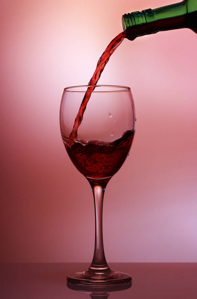 Rotwein in Nahaufnahme in das Weinglas gießen, isoliert auf rosa g - Foto, Bild