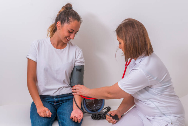 Médico femenino midiendo la presión arterial de su joven adolescente
 - Foto, imagen