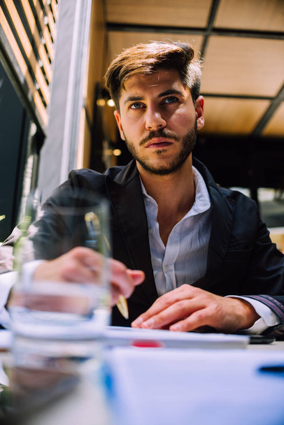 Бізнесмен читає документ. Молодий чоловік сидить за своїм столом, проходячи контракт
 - Фото, зображення