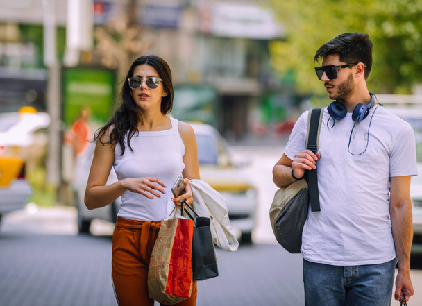 Jovem casal feliz com sacos de compras enquanto caminha na cidade
 - Foto, Imagem