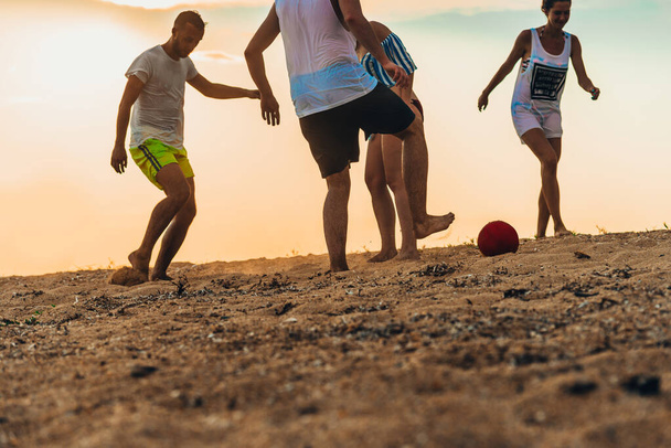 Ομάδα φίλων που παίζουν ποδόσφαιρο σε αμμώδη παραλία στις καλοκαιρινές διακοπές - Φωτογραφία, εικόνα