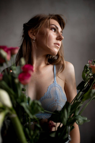 Beautiful young woman in lace blue underwear holds rose flowers, skin care concept - Fotografie, Obrázek