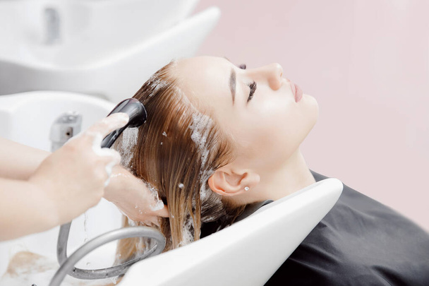 Mulher loira bonita recebendo lavagem de cabelo no salão de beleza
 - Foto, Imagem