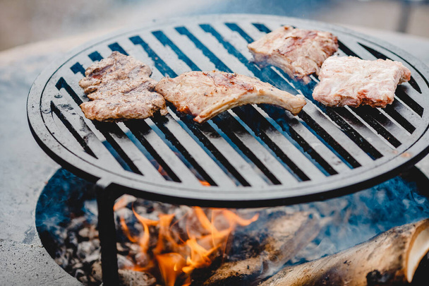 Varkensribbetjes en steak gekookt op grill, open vuur straat voedsel festival - Foto, afbeelding