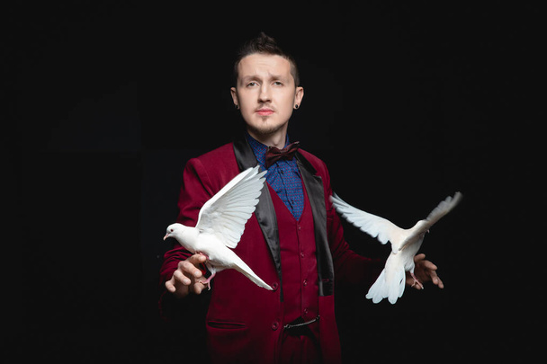 Kouzelník muž ukazuje trik s vyškolenými dvě bílé holubice pták - Fotografie, Obrázek