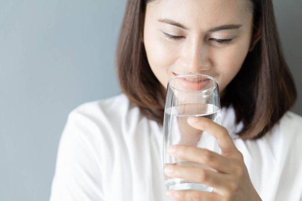 Sluiten vrouw drinken zuiver water uit glas met licht in de ochtend, Selectieve focus - Foto, afbeelding