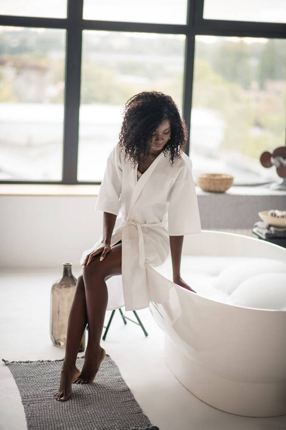 Woman sitting near bath with foam in the morning - Fotó, kép