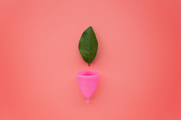 Menstruatiecup op roze achtergrond. Alternatief vrouwelijk hygiëneproduct tijdens de periode. Vrouwen gezondheidsconcept. Begrepen, ruimte. Milieuvriendelijk concept, afvalvrij product. Vlakke lay-up, model, sjabloon - Foto, afbeelding