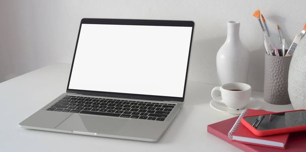 Otwórz pusty ekran laptopa w nowoczesnym obszarze roboczym z dekoracjami ceramicznymi i materiałami biurowymi  - Zdjęcie, obraz