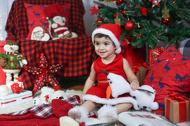 Frohe Weihnachten und ein gutes neues Jahr! Porträt eines emotionalen Kindes im Neujahrskostüm. Kleinkind-Mädchen im geschmückten Raum mit Christbaum und Neujahrsschmuck. - Foto, Bild