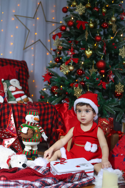 Feliz Natal e Feliz Ano Novo! Retrato de uma criança emocional em um traje de Ano Novo. Menina criança no quarto decorado com árvore de Natal e decorações de ano novo
. - Foto, Imagem