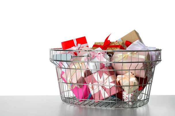Shopping basket full of gift boxes on light grey table against white background - Fotoğraf, Görsel