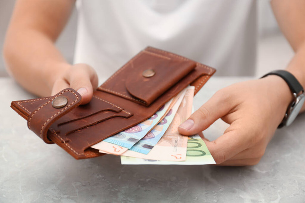 Чоловік кладе купюри євро в гаманець, пристібається. - Фото, зображення