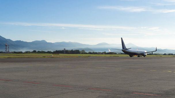 Літак на злітно-посадковій смузі готується до зльоту рано вранці в аеропорту в горах
 - Фото, зображення