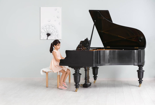 Маленькая девочка играет на рояле в помещении
 - Фото, изображение