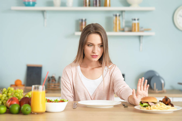 Woman refusing to eat unhealthy food in kitchen. Diet concept - Foto, afbeelding
