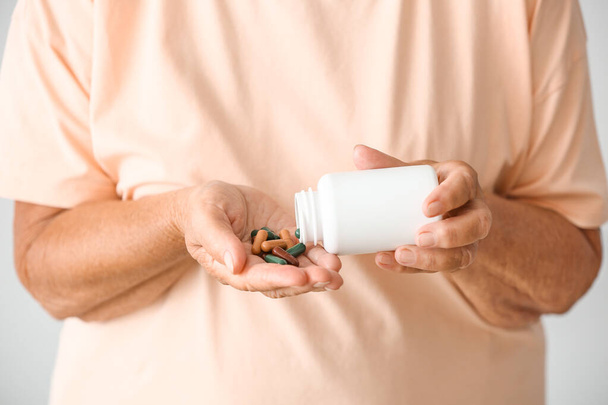 Mulher idosa com pílulas no fundo claro, close-up
 - Foto, Imagem
