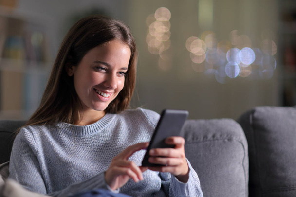 Happy woman checking mobile phone content at home - Foto, Imagen