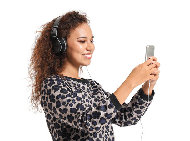 Όμορφη Αφροαμερικανή γυναίκα που ακούει μουσική σε λευκό φόντο - Φωτογραφία, εικόνα