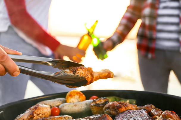 Friends cooking tasty food on barbecue grill outdoors, closeup - 写真・画像