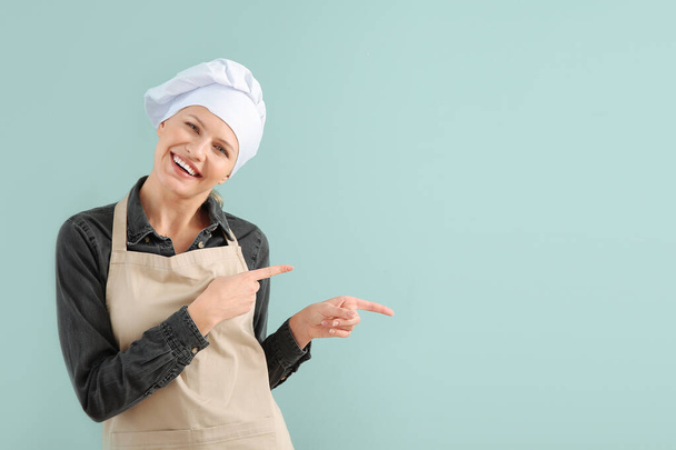 Bella chef femminile che punta a qualcosa sullo sfondo di colore
 - Foto, immagini