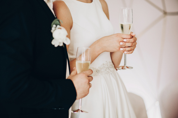 Stylish wedding couple holding champagne glasses and toasting at - Photo, Image