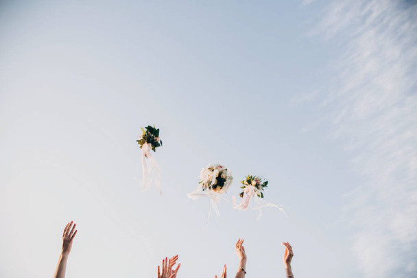 Bruid en bruidsmeisjes gooien bruidsboeketten in de lucht in - Foto, afbeelding