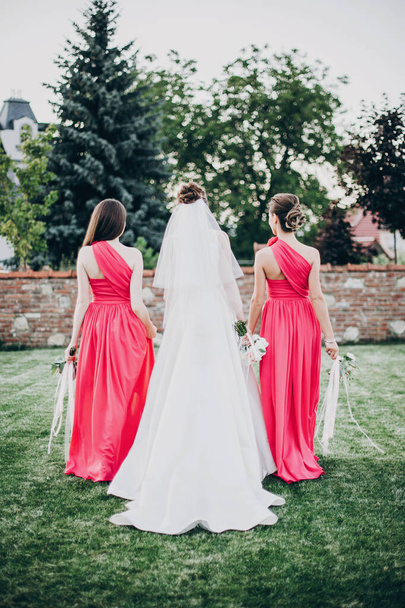 Prachtige bruid wandelen met bruidsmeisjes in roze jurken, met - Foto, afbeelding