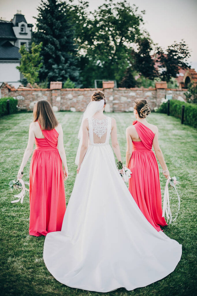 Чудова наречена гуляє з подружками нареченої в рожевих сукнях, тримаючи
 - Фото, зображення