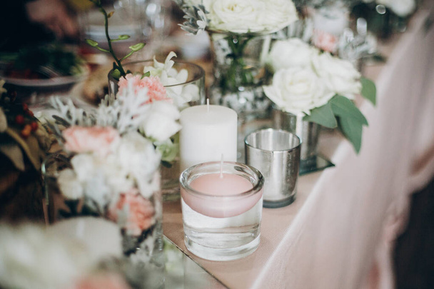 Candle, White  flowers in modern glass vase on pink centerpiece. - Фото, изображение