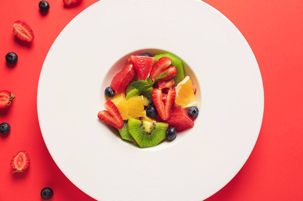 Piatto con gustosa macedonia di frutta su sfondo a colori
 - Foto, immagini