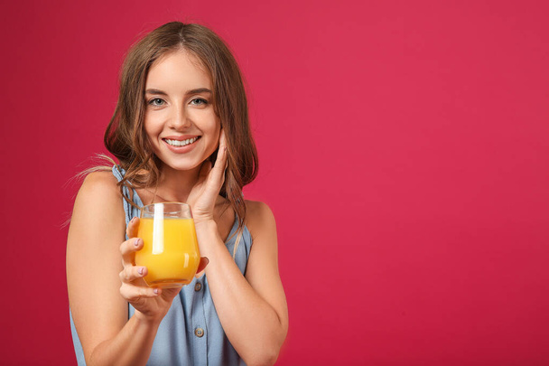 Όμορφη νεαρή γυναίκα με χυμό πορτοκάλι στο φόντο χρώμα - Φωτογραφία, εικόνα