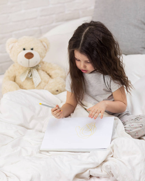 cute little girl drawing pictures while lying on bed - Foto, Bild