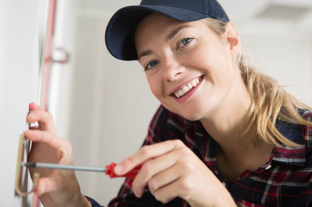 happy female technician is screwing an electric socket - Foto, Imagem