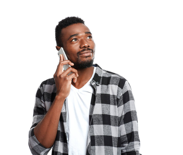 Portrait of handsome African-American man talking by mobile phone on white background - Photo, Image