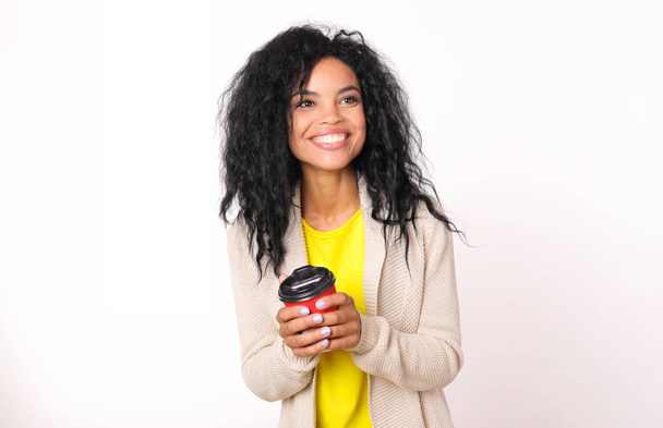 beautiful mixed race woman in casual clothes holding coffee to go cup and posing on white studio background  - Fotoğraf, Görsel