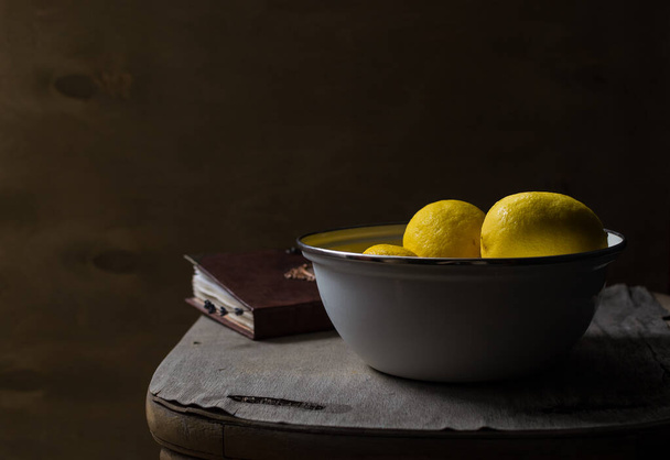 Cuenco de limones frescos y un libro
 - Foto, Imagen