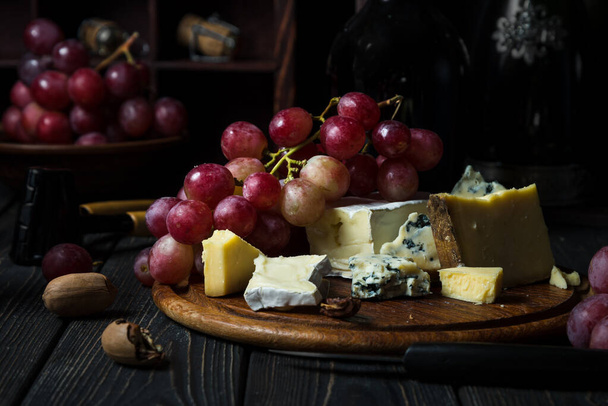 kaas en druiven op houten tafel - Foto, afbeelding