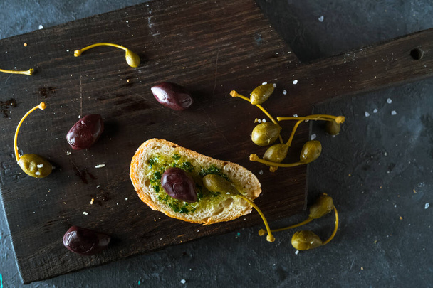 čerstvý chléb s olivami a kapary na tmavém pozadí - Fotografie, Obrázek