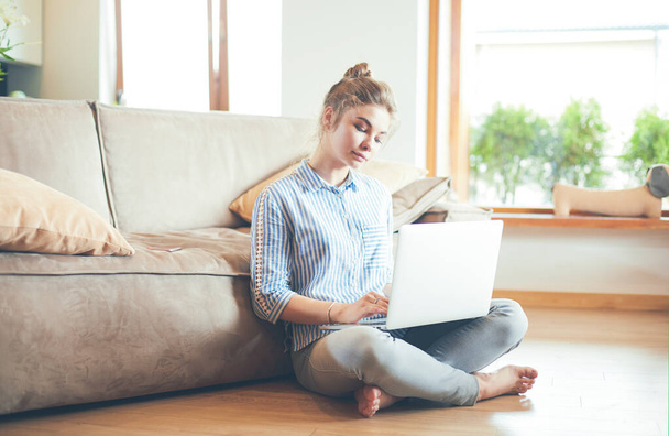 Happy woman with laptop on living room floor - Foto, imagen