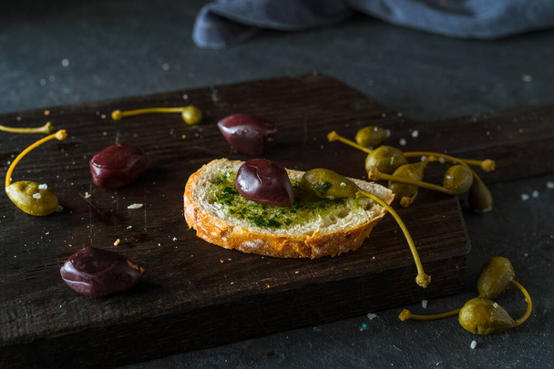 pane fresco con olive e capperi su fondo scuro
 - Foto, immagini
