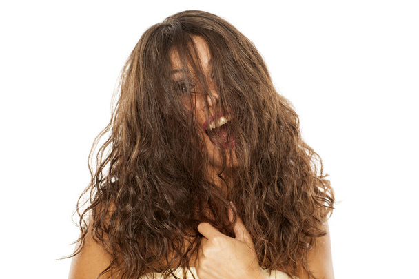Νεαρή ευτυχισμένη γυναίκα με τα μαλλιά της στο πρόσωπό της - Φωτογραφία, εικόνα