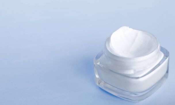 Frasco hidratante de creme facial em fundo azul, pele hidratante
 - Foto, Imagem