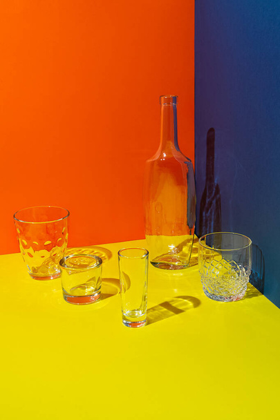 glasses and empty bottle on bright orange yellow background - Foto, Bild