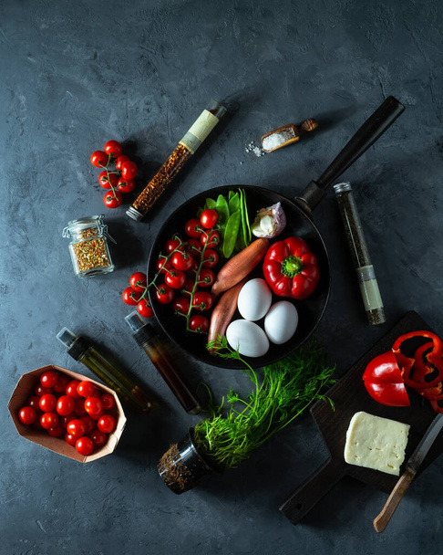 fresh vegetables and chicken eggs in frying pan on dark background - 写真・画像
