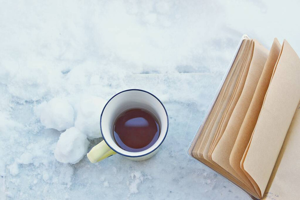 Tasse à café jaune, planificateur quotidien en papier brun, boules de neige sur une planche de marbre avec neige autour
 - Photo, image