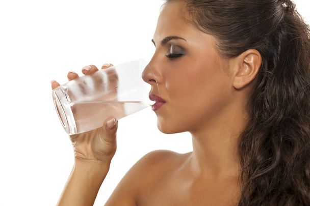 Μια νεαρή γυναίκα πίνει κρύο νερό από το ποτήρι. - Φωτογραφία, εικόνα