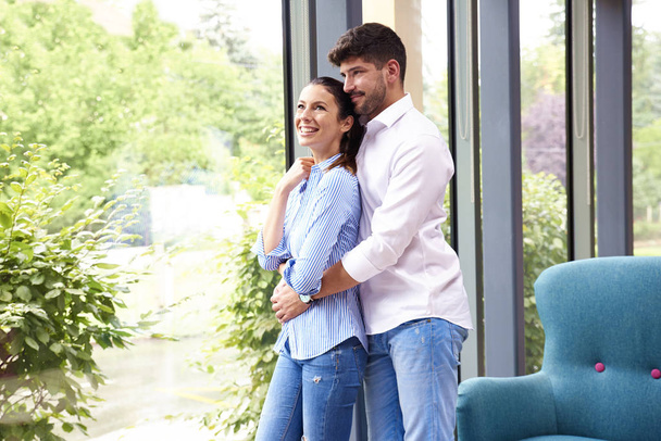 Shot of beautiful young couple standing in living room and looki - 写真・画像